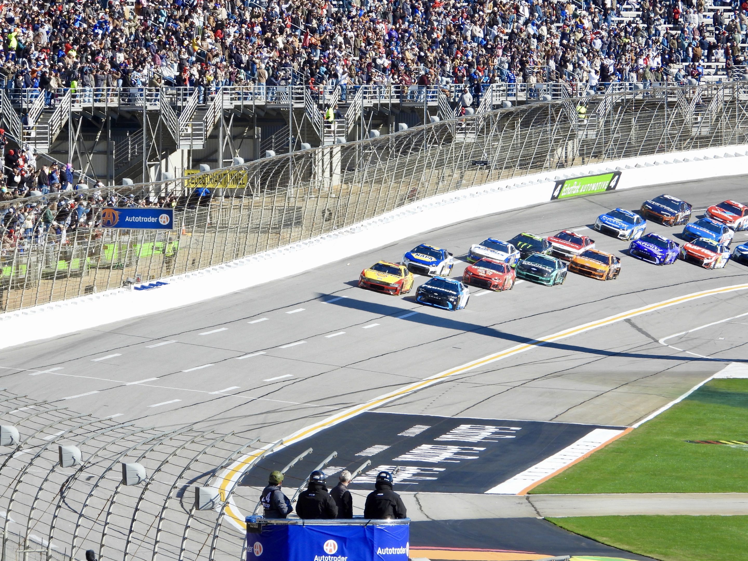 The NASCAR Cup Series field thunders past the packed grandstands towards the flag stand at EchoPark Speedway in Atlanta